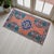 This charming vintage Oushak mat features a soft, sun-faded terracotta field accented by vibrant turquoise and deep...