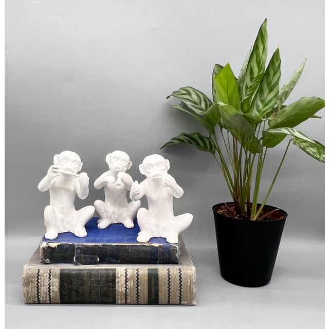 A set of three vintage Fitz and Floyd monkey musician figurines in glossy white glazed ceramic, depicting a flutist, horn...