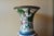 This tall decorative vase features a classic silhouette accented with green and purple decorative detailing, making it a...
