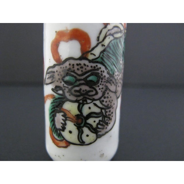 Vintage Chinese porcelain snuff bottle with hand painted enamel foo dog and unraveling ribbon ball design. Polished dome...
