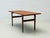 A simple coffee table in the style of the 1970s with clean lines and a warm wood look. The rectangular tabletop features a...