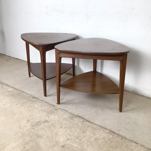 A well-matched pair of two-tier end tables in the mid-century modern tradition, each with a shield-form triangular top...