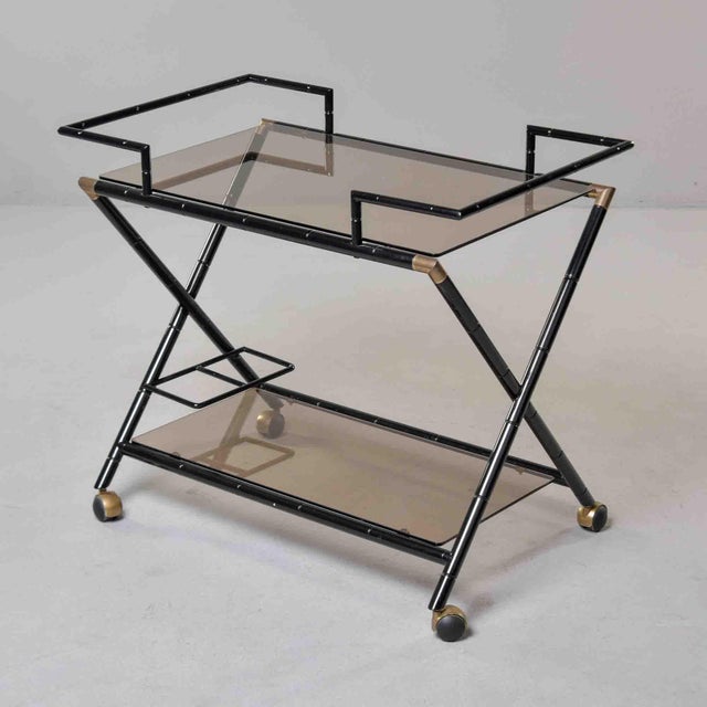 This two-tier bar trolley is constructed in black-lacquered metal cast to simulate bamboo segmentation throughout. The top...