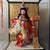 This refined Japanese doll is presented in a glass display case with a black lacquered wooden frame, opening from the top...