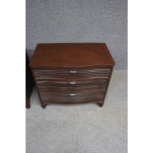 Pair of Brownstone nightstands with curved fronts and reeded drawer fronts. Finished in a warm medium-dark wood tone with...