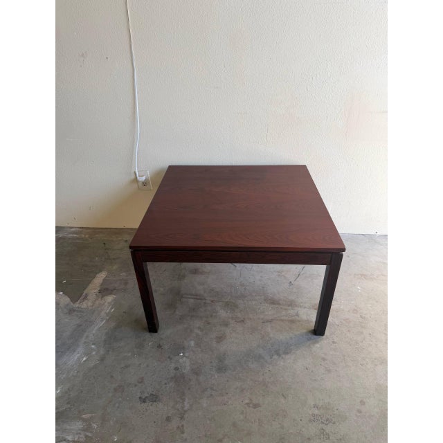 Danish Mid-Century Modern coffee table crafted in richly grained rosewood. This piece features a clean square silhouette...