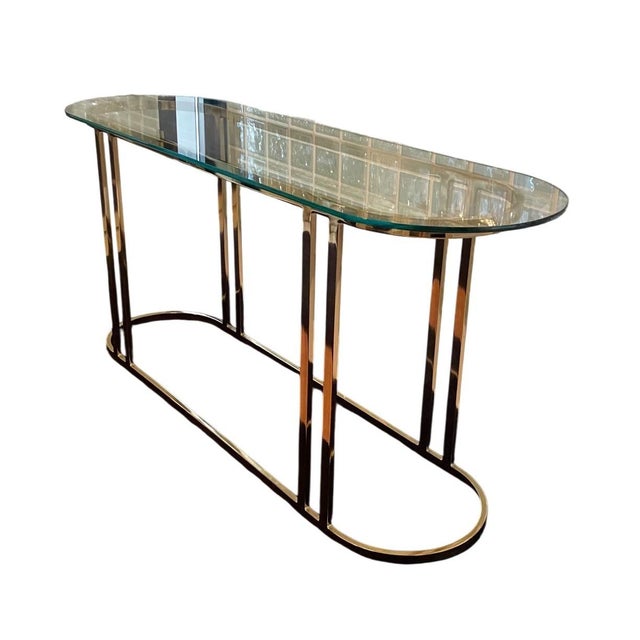 Hollywood Regency Elliptical Brass Console Table Dims: 56"W x 18"D x 26.5"H This classic item is a modern brass and glass...
