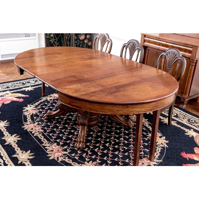 An antique extension dining table with a warm-toned, medium brown patina, two 17” extension leaves, thick cylindrical...