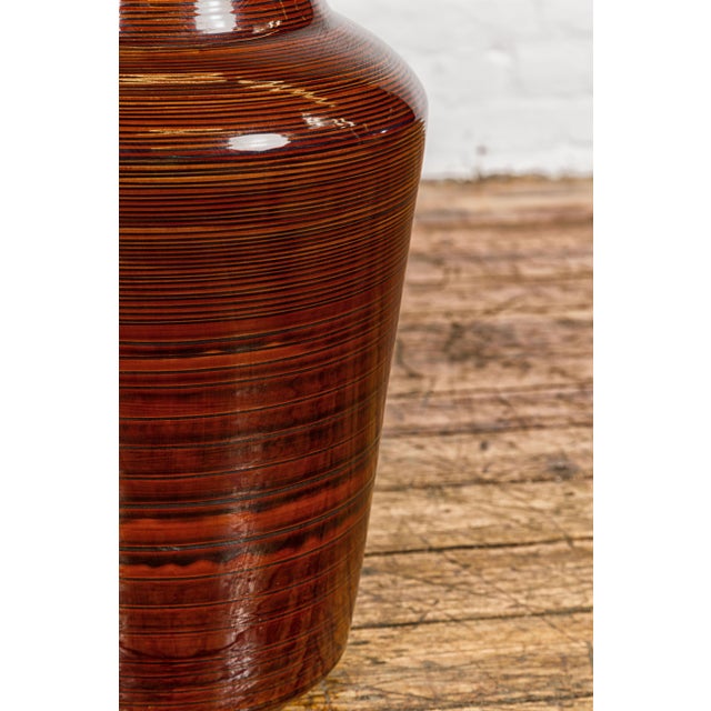 An artisan brown glaze vase with black concentric motifs and tapering lines. This contemporary artisan vase captivates...