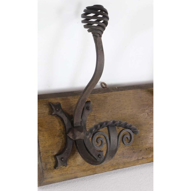 A European wall rack featuring three curled wrought iron hooks mounted on a wood base. This piece combines traditional...