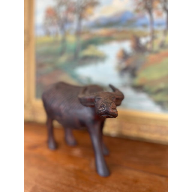 This vintage wooden sculpture depicts a water buffalo, meticulously hand-carved from a single piece of hardwood. The...
