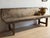 A rare and exceptional 18th-century Spanish Catalan bench, hand-hewn from solid chestnut with a deeply worn surface that...
