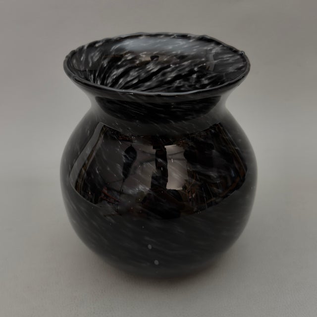 A striking, curved blown glass decorative vase, featuring a refined swirling pattern with nuanced transparencies, typical...
