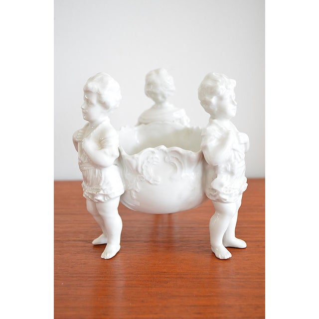 Centerpiece - Bowl with three cherubs The centerpiece is made of white porcelain and bears a model number 10 on the bottom...