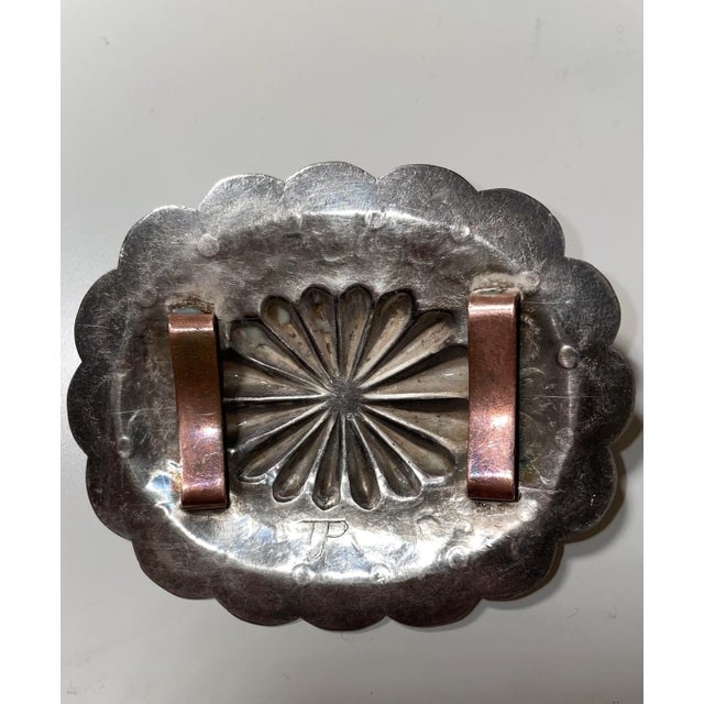 This handmade Navaho Silver belt buckle is adorned with a turquoise cabouchon. It is signed by TJP by the Navaho artist.