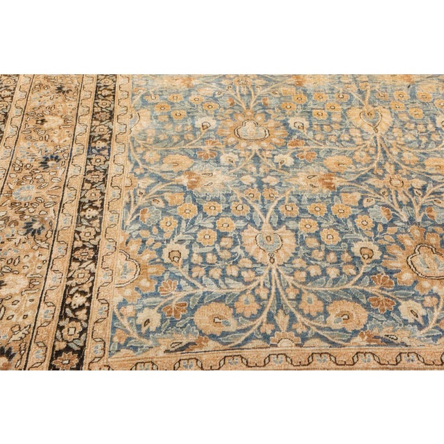 An early 20th century Mashad Persian rug the green-blue field with a lively palmette and flowering vine trellis overall...