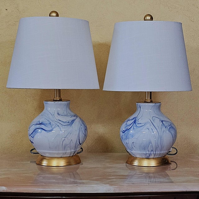 Pair of Jonathan Y “Holly” marbleized ceramic table lamps featuring soft blue and white swirling glaze patterns accented...