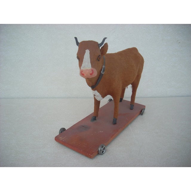 Hide is made of felt; this cow pull toy rides on a salmon stained wheeled cart and possess an air bellow ( in working...
