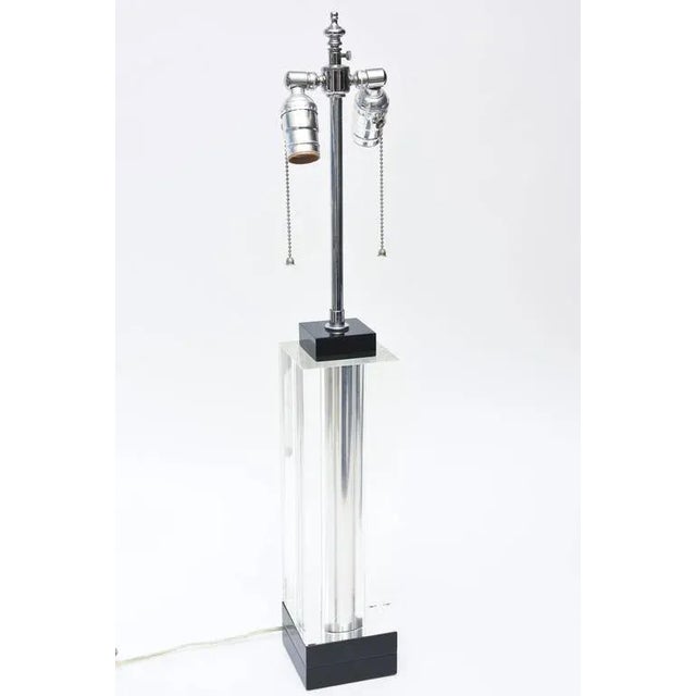 This handsome and modern square column lucite lamp is clear in the center banded by a black lucite base and top. It has a...