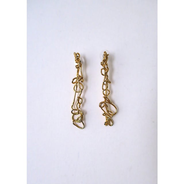 A pair of gold-tone abstract long drop earrings. Pair measure 3.13" long. For pierced ears. Dress up or down.