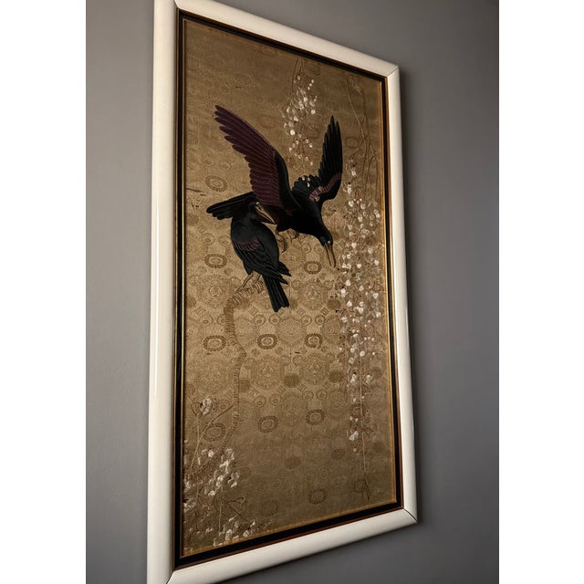 A striking vintage hand-embroidered silk panel depicting two black birds in flight against an intricately woven gold...