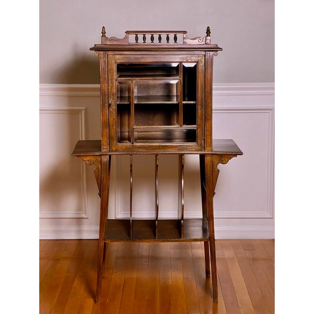A unique music or display cabinet in walnut with an easel stand and beveled glass door, circa 1910s. A beautifully shaped...