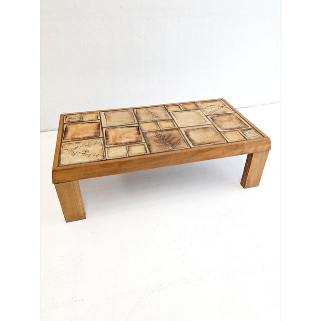 Vintage coffee table from the 1960s featuring a solid oakwood frame with a distinctive decorative tiled top. It was made...
