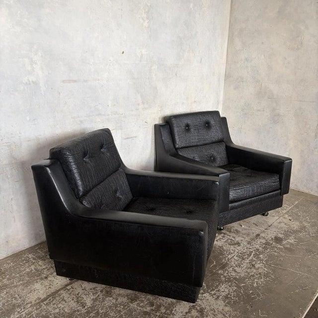 A matching pair of Art Deco club armchairs with broad sculptural arms, deep buttoned seats and individually upholstered...
