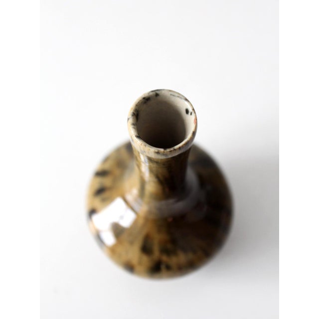 This vintage handmade studio pottery vase has a softly rounded form and a narrow neck, finished in a warm glaze of layered...
