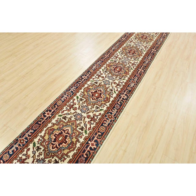 A traditional tribal Heriz runner hand-knotted with an all-wool pile on a cotton foundation. This oriental rug features a...