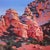This artwork depicts a striking landscape of rugged rock formations bathed in warm hues of orange and red, contrasted by...