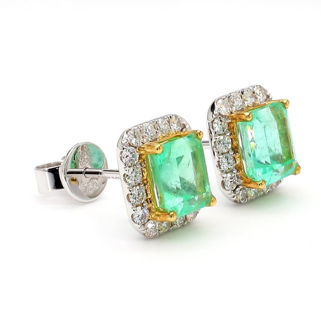 A matched pair of emerald cut natural emerald halo stud earrings in 18K two-tone white and yellow gold, featuring a 1.36...
