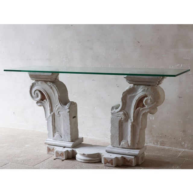 Console table composed of authentic baroque marble elements paired with a clear glass top. The base consists of heavy...