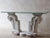 Console table composed of authentic baroque marble elements paired with a clear glass top. The base consists of heavy...