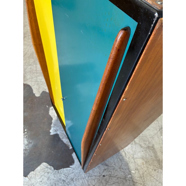 Fantastic MCM two-tone armoire cabinet, featuring turquoise and yellow sliding doors that open to shelving on one side and...