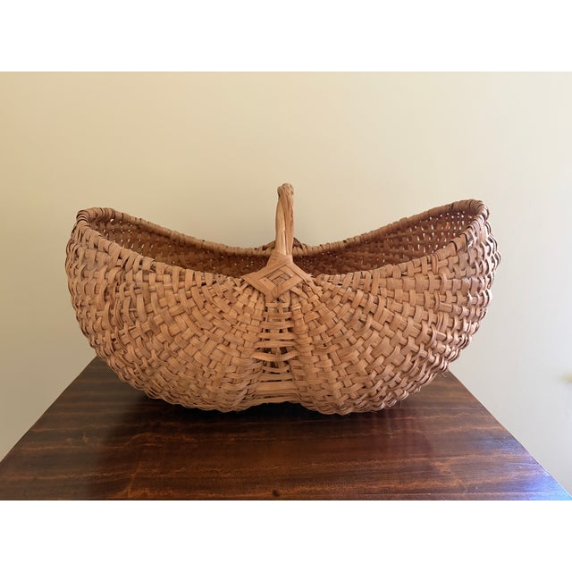 A generously scaled early 20th-century American gathering basket, handwoven from oak splints in the traditional buttocks...