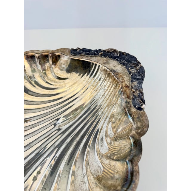 A large vintage silver-plated centerpiece bowl featuring an elegant scallop shell form with deeply fluted sides and a...