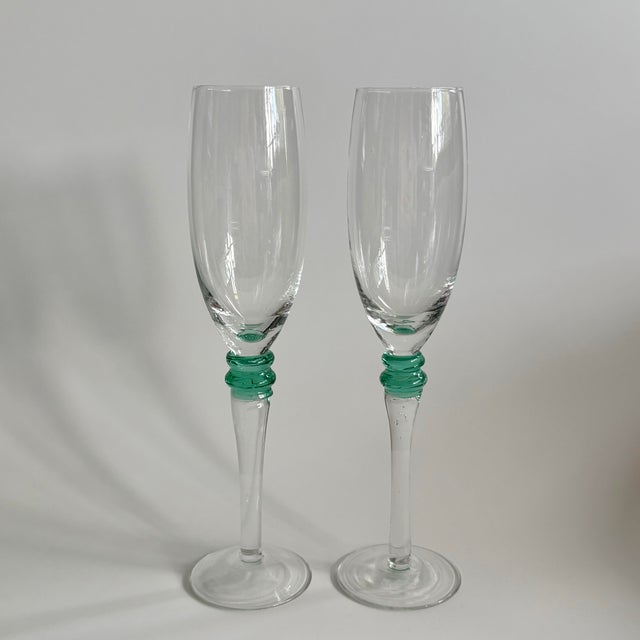Refined pair of vintage champagne flutes that feature delicate clear glass bowls and green rings at the stem. With clean...