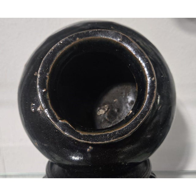 A charming antique miniature Chinese black-glazed stoneware jar, showcasing the timeless appeal of traditional folk...