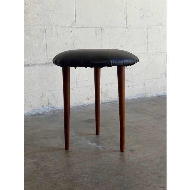 This round tripod footstool features a minimalist silhouette and three tapered legs. The compact design allows for...