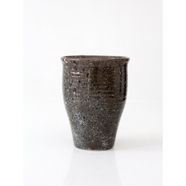 This vintage handmade studio pottery vase has a tapered wheel-thrown form with a gently flared rim and a charcoal gray...