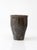 This vintage handmade studio pottery vase has a tapered wheel-thrown form with a gently flared rim and a charcoal gray...