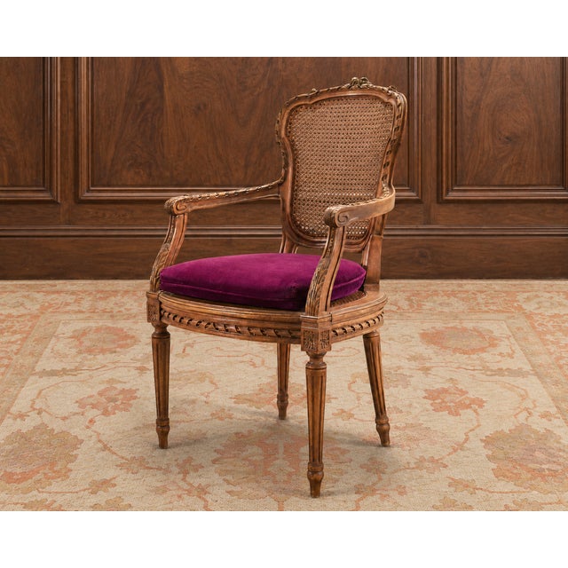 An elegant walnut and cane fauteuil armchair crafted in the grand French Louis XVI style. The distinctive chair features a...