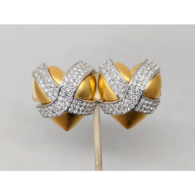 1980s matte goldtone puffy hearts with pavé round clear rhinestone x through them set in rhodium plate clip earrings....