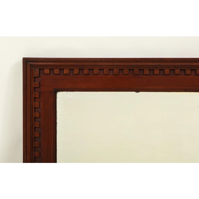 The beveled rectangular mirror plate within a conforming solid mahogany frame, boldly carved with dentil banding. Handsome...