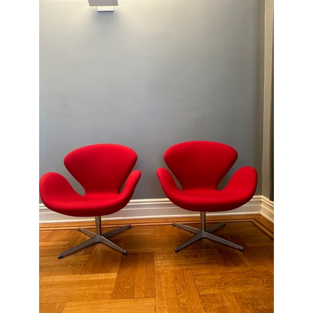 Pair of authentic red fabric Swan Chairs in excellent condition. Designed by Arne Jacobsen and produced by Fritz Hansen....