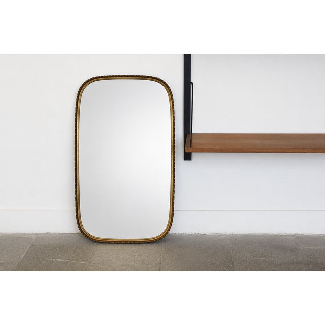 An elegant wall mirror from the 1950s, featuring the timeless aesthetic of post-war modernism. Its form is based on a...