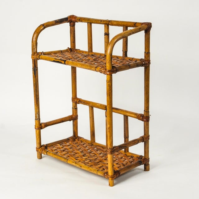 A small vintage wall hanging etagere in tortoise shell bamboo with two woven shelves. Beautiful bentwood curves and lines,...