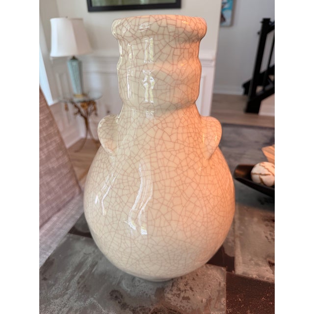 Large decorative ceramic vase featuring a warm ivory crackle glaze with an elegant rounded silhouette and sculptural...