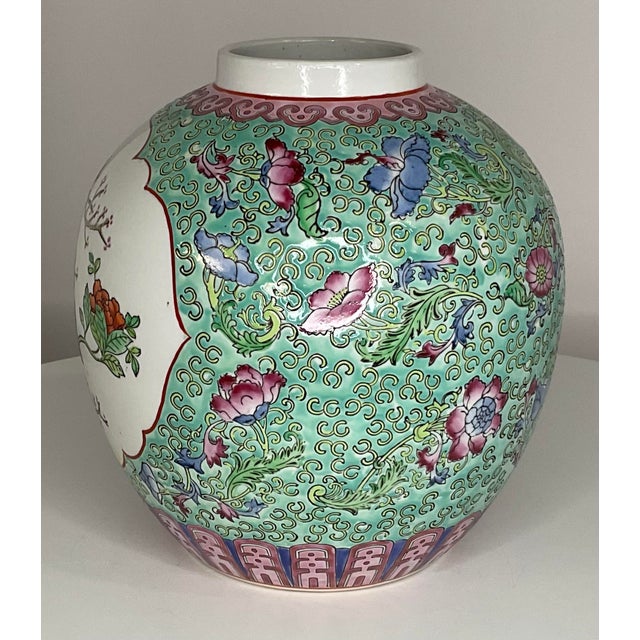Chinoiserie vase features flowers and birds on brightly colored vessel. Flowers in various shades of blue and pink on a...